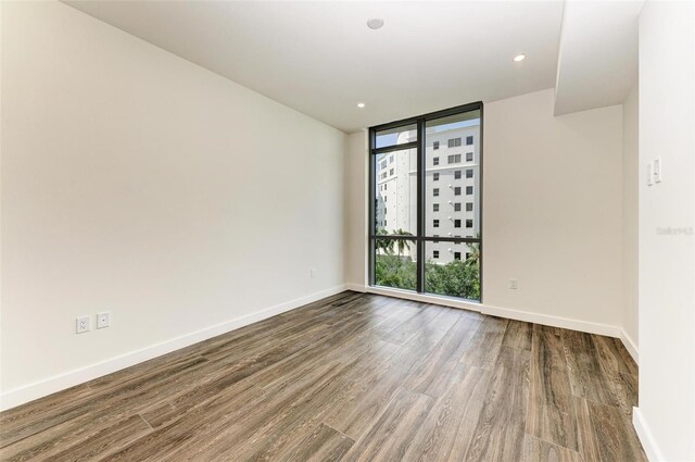 unfurnished room featuring a wall of windows, recessed lighting, dark wood finished floors, and baseboards