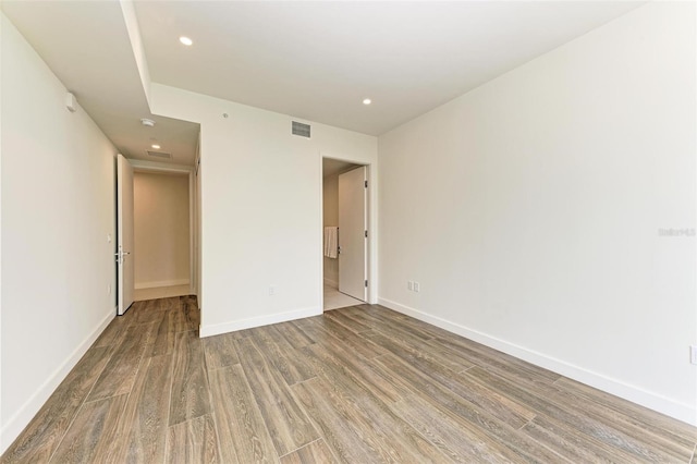 spare room with baseboards, visible vents, wood finished floors, and recessed lighting