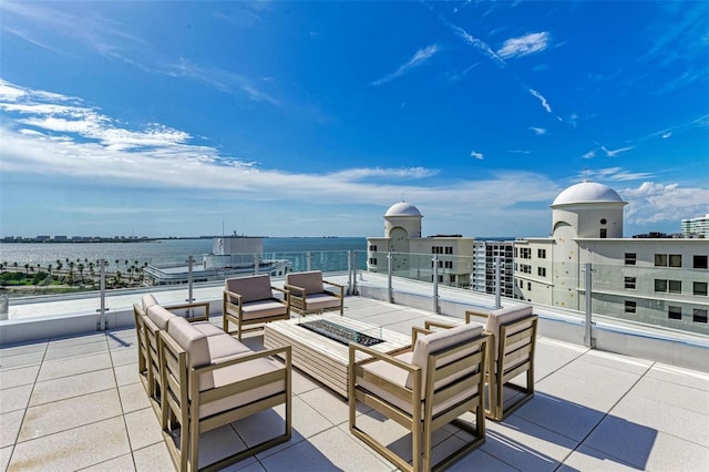 view of patio / terrace with a water view, a view of city, and an outdoor living space with a fire pit