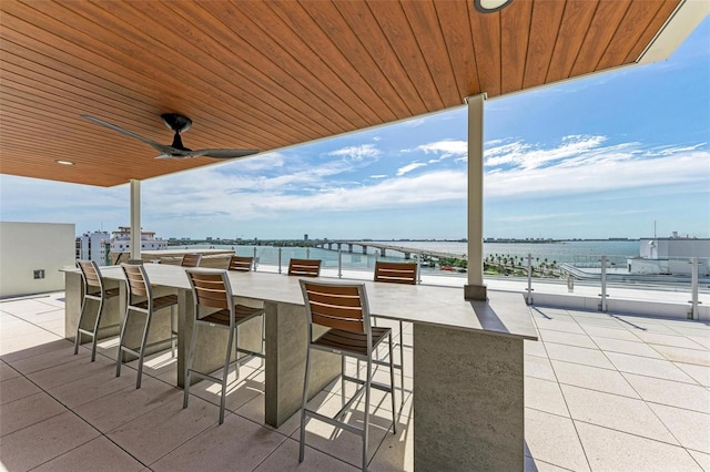 view of patio / terrace with a water view, ceiling fan, and a bar