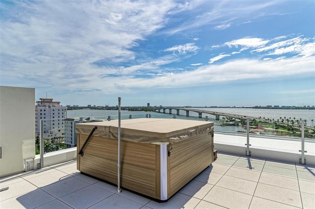 view of patio / terrace featuring a view of city, a water view, a balcony, and a hot tub