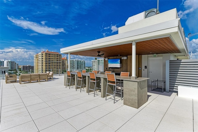 view of patio with outdoor dry bar, a view of city, and a ceiling fan