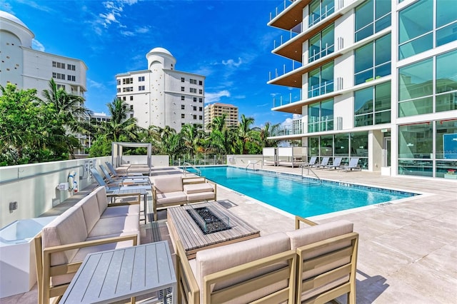 pool featuring an outdoor living space with a fire pit and a patio area