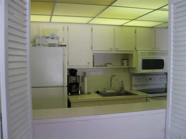 kitchen featuring white appliances, white cabinetry, sink, and a paneled ceiling