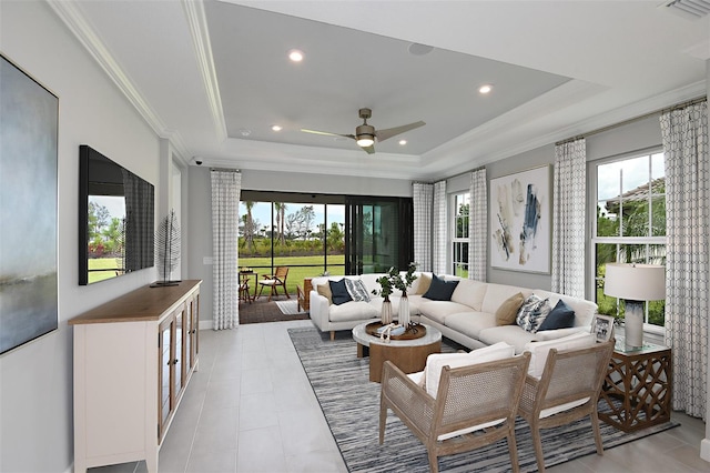 tiled living room with ceiling fan, a raised ceiling, crown molding, and a wealth of natural light