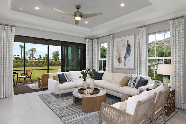 tiled living room featuring a tray ceiling, ceiling fan, and crown molding