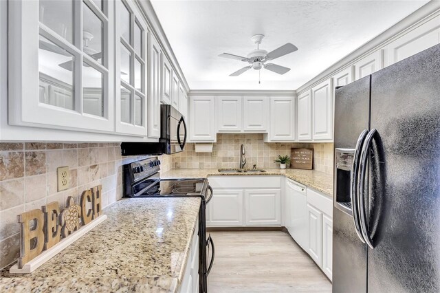 kitchen with black appliances, light stone countertops, white cabinetry, and sink