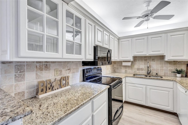 kitchen with black appliances, sink, light stone countertops, light hardwood / wood-style floors, and white cabinetry