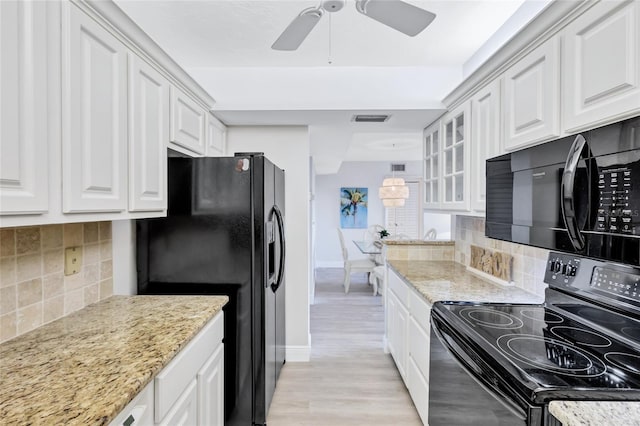 kitchen featuring black appliances, white cabinets, light stone countertops, and backsplash