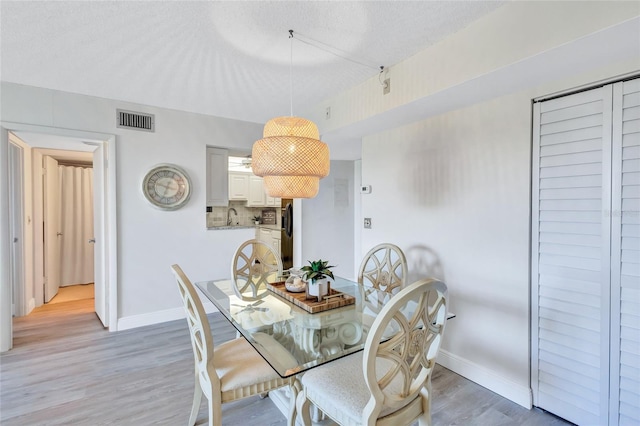 dining space featuring light hardwood / wood-style flooring, a textured ceiling, and sink