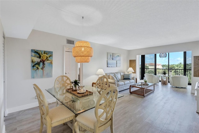 dining space with light hardwood / wood-style flooring and a textured ceiling