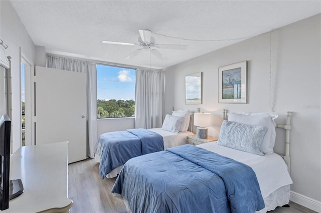 bedroom with a textured ceiling, light wood-type flooring, and ceiling fan