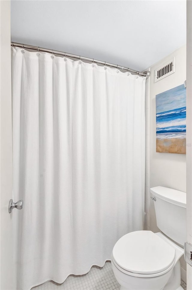 bathroom with tile patterned floors, walk in shower, and toilet