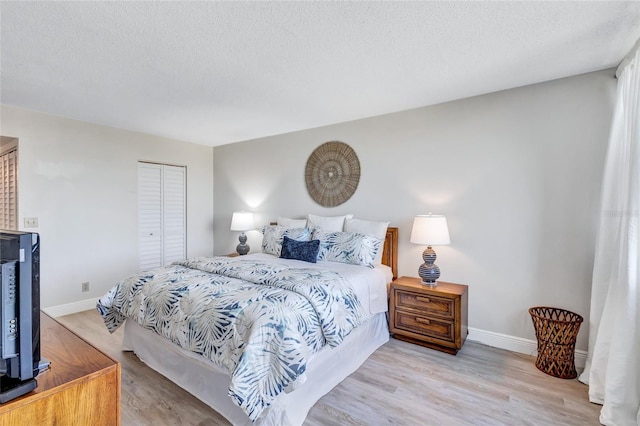 bedroom featuring light hardwood / wood-style floors, a textured ceiling, and a closet