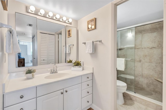 bathroom featuring tile patterned flooring, vanity, toilet, and walk in shower