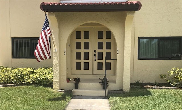 1446 56th St W Unit 1446, Bradenton, FL 34209 - view of exterior entry featuring stucco siding, a tile roof, and a lawn