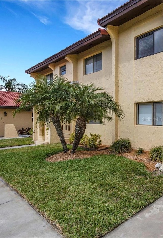 1446 56th St W Unit 1446, Bradenton, FL 34209 - view of property exterior with stucco siding, a tile roof, and a yard