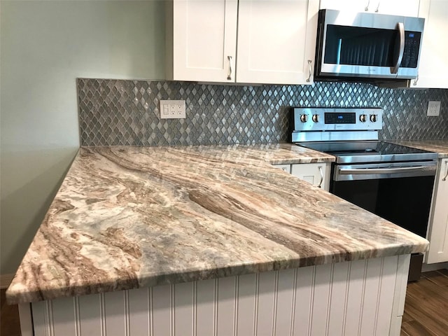 kitchen with light stone countertops, white cabinets, and stainless steel appliances