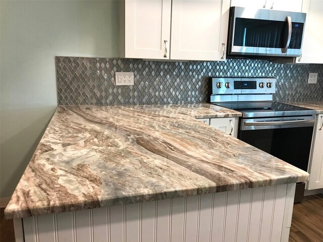 1446 56th St W Unit 1446, Bradenton, FL 34209 - kitchen featuring appliances with stainless steel finishes, light stone counters, dark wood-style floors, a peninsula, and white cabinetry