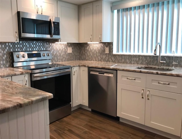 kitchen with light stone countertops, stainless steel appliances, white cabinets, and sink