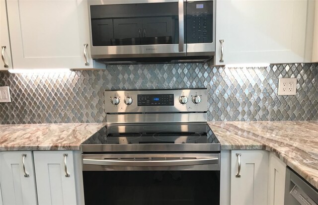 kitchen with light stone counters, white cabinetry, backsplash, and appliances with stainless steel finishes