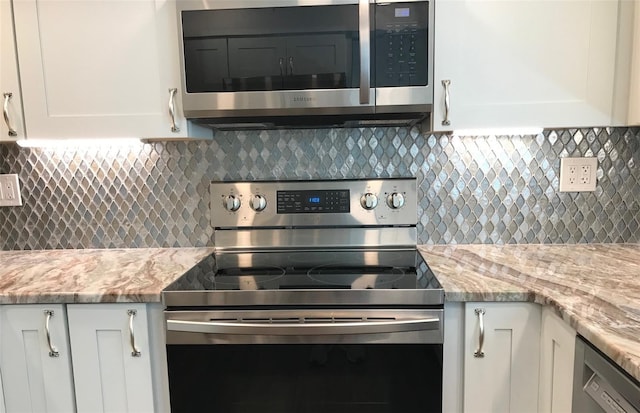 1446 56th St W Unit 1446, Bradenton, FL 34209 - kitchen view of stainless steel appliances, decorative backsplash, white cabinets, and light stone counters