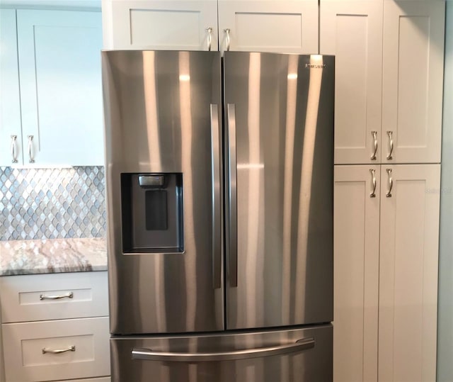 kitchen featuring white cabinets, stainless steel fridge, and light stone countertops