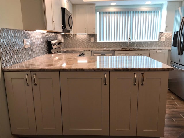 kitchen featuring light stone countertops, tasteful backsplash, stainless steel appliances, sink, and white cabinets