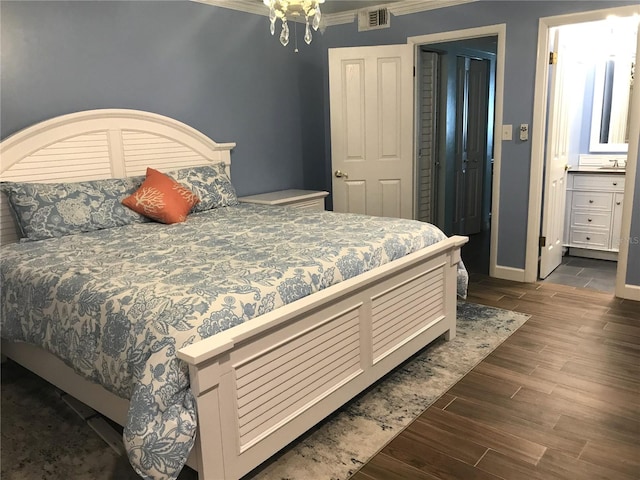 bedroom featuring dark hardwood / wood-style floors, crown molding, connected bathroom, and an inviting chandelier