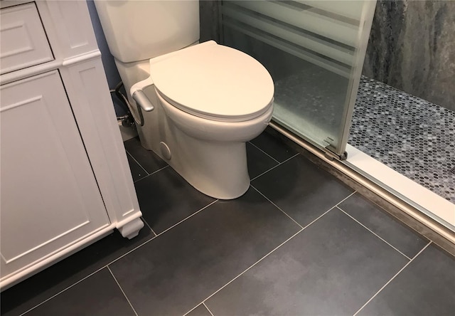 bathroom with tile patterned flooring, toilet, and walk in shower