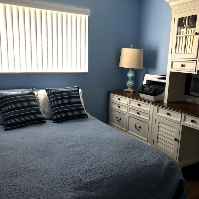 bedroom with dark colored carpet and multiple windows