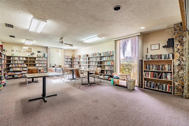 interior space featuring ceiling fan, carpet floors, and a textured ceiling