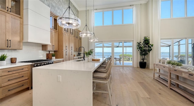 kitchen with decorative light fixtures, a water view, ornamental molding, and plenty of natural light