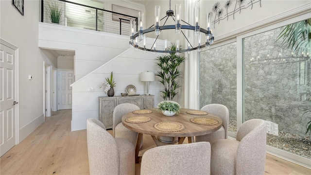 dining space featuring a chandelier, a high ceiling, and light hardwood / wood-style flooring