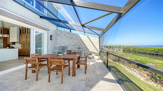 view of patio with a water view, area for grilling, and exterior kitchen