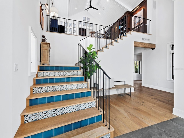 staircase with wood ceiling, ceiling fan, wood-type flooring, beam ceiling, and high vaulted ceiling