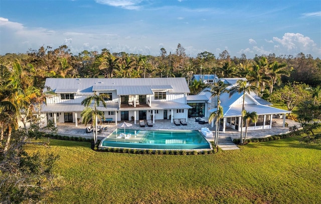 rear view of property featuring a lawn, a balcony, and a patio