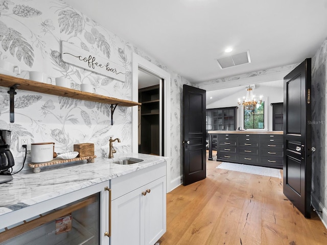 kitchen featuring sink, an inviting chandelier, white cabinets, light hardwood / wood-style floors, and hanging light fixtures