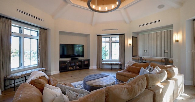 living room with vaulted ceiling with beams, light hardwood / wood-style floors, and a chandelier