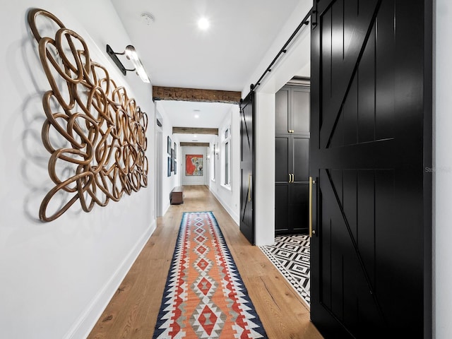 hall with a barn door and light hardwood / wood-style floors