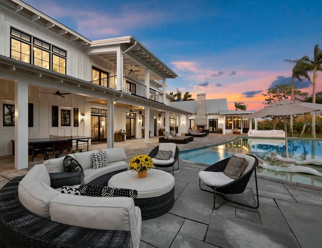 pool at dusk featuring ceiling fan, an outdoor hangout area, and a patio