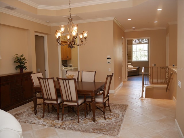 tiled dining area with independent washer and dryer, a notable chandelier, and ornamental molding