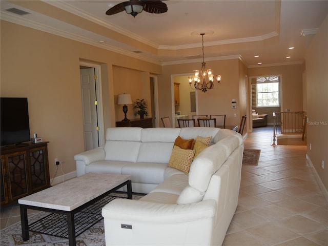 living room featuring a tray ceiling, light tile patterned floors, ornamental molding, and ceiling fan with notable chandelier