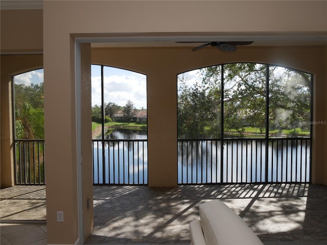 unfurnished sunroom with ceiling fan and a water view