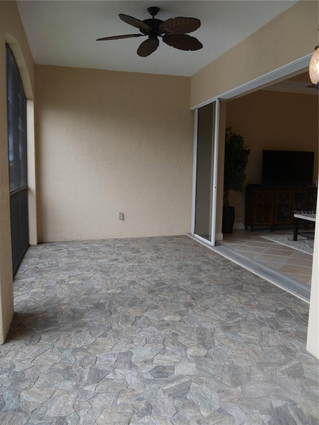 unfurnished sunroom featuring ceiling fan