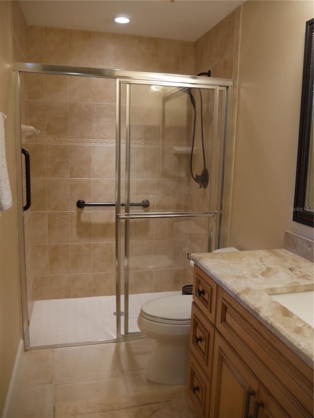 bathroom featuring toilet, an enclosed shower, vanity, and tile patterned flooring