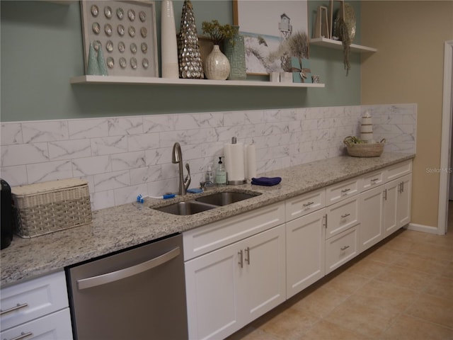 kitchen with white cabinets, decorative backsplash, sink, stainless steel dishwasher, and light stone countertops