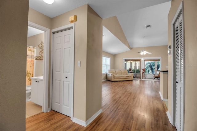 corridor featuring hardwood / wood-style floors, lofted ceiling, and a wealth of natural light