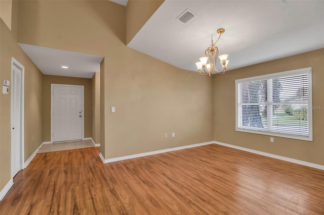 spare room with light wood-type flooring and a notable chandelier