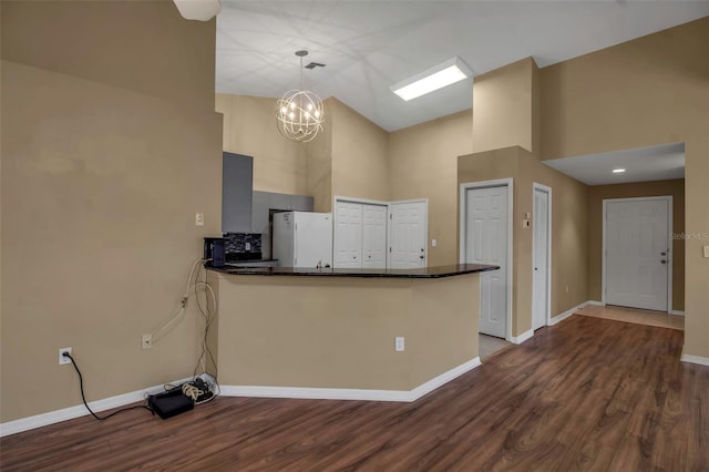 kitchen featuring pendant lighting, white fridge, kitchen peninsula, and a towering ceiling